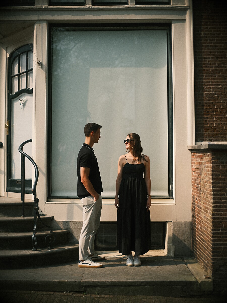 Engagement SP4 Elegant verlovingsportret van een koppel in zwarte outfits naast een hoog raam van een Amsterdams grachtenpand