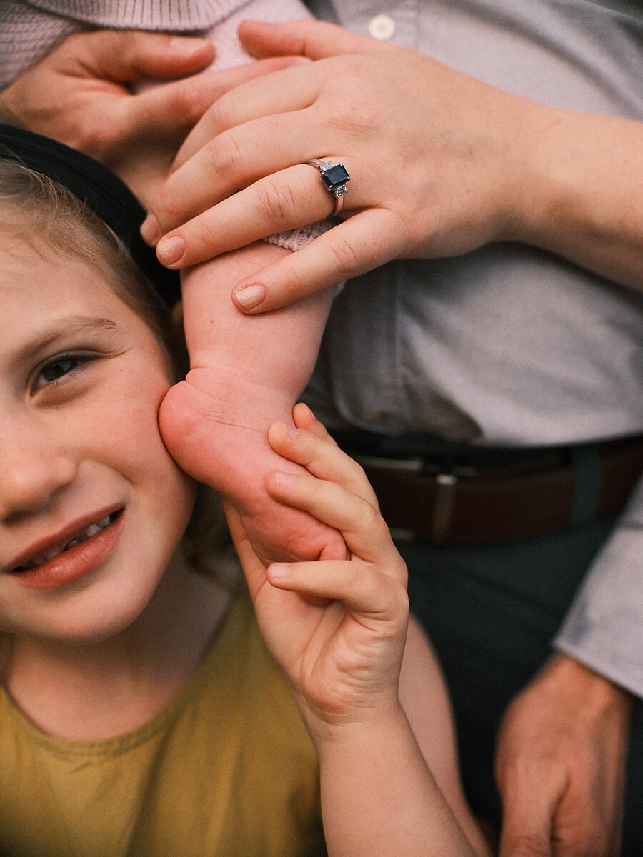 Family SP11 Ongedwongen detailopname van een babyvoetje tegen de wang van een lachend broertje of zusje, een lief detail uit een familie fotosessie