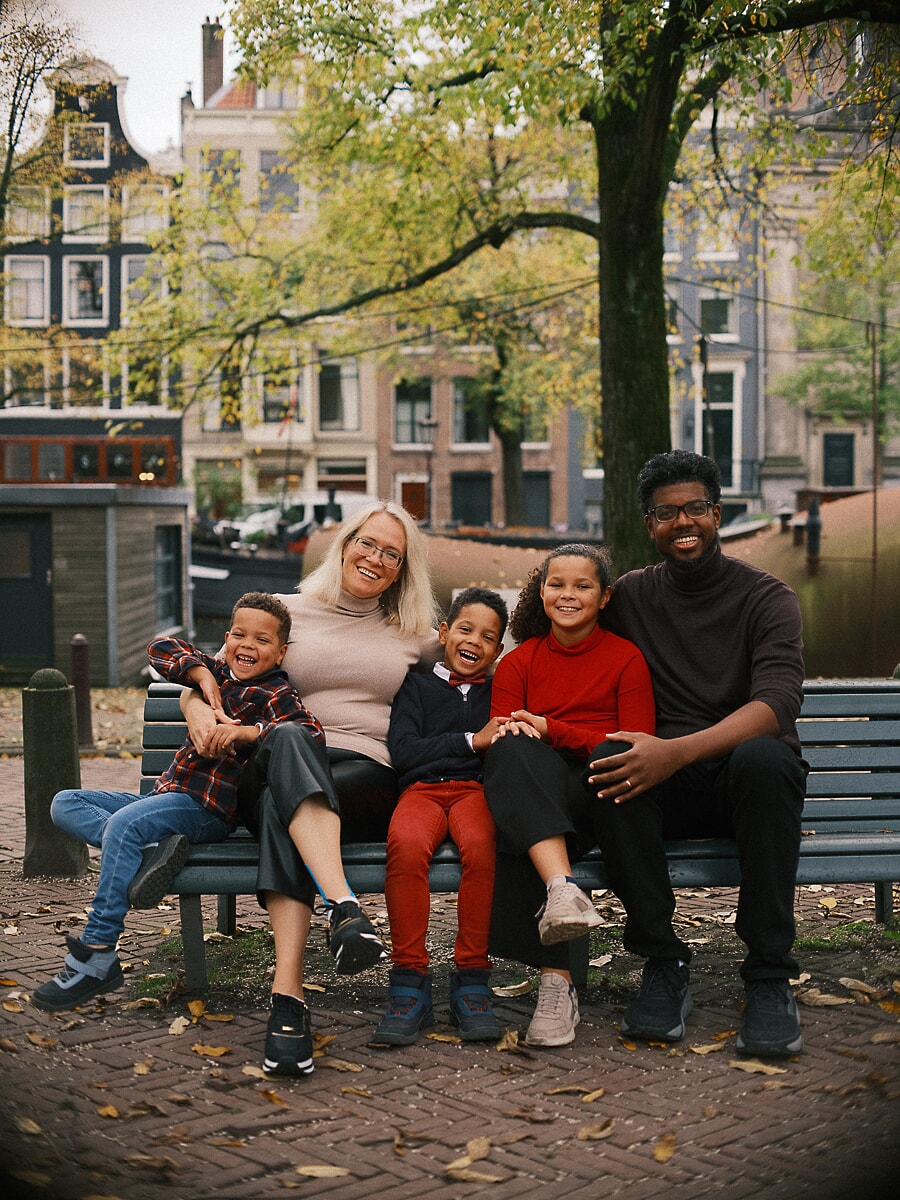 Family SP3 Familie met meerdere generaties lacht samen op een bank aan de gracht in de herfst, een oma omringd door haar kleinkinderen tijdens hun familiefotografie sessie
