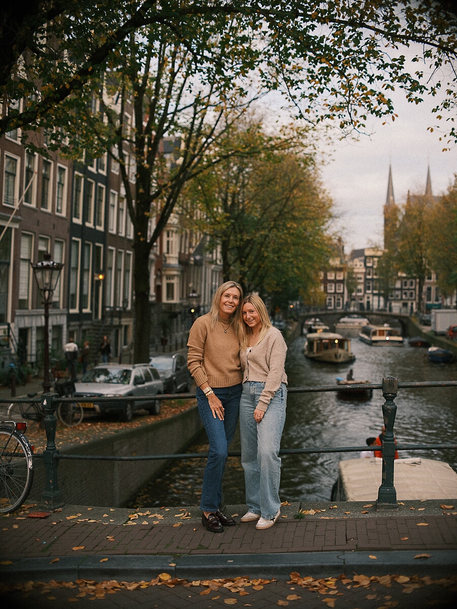 Family SP9 Moeder en tienerdochter leunen tegen elkaar voor een portret op een Amsterdamse brug in de herfst