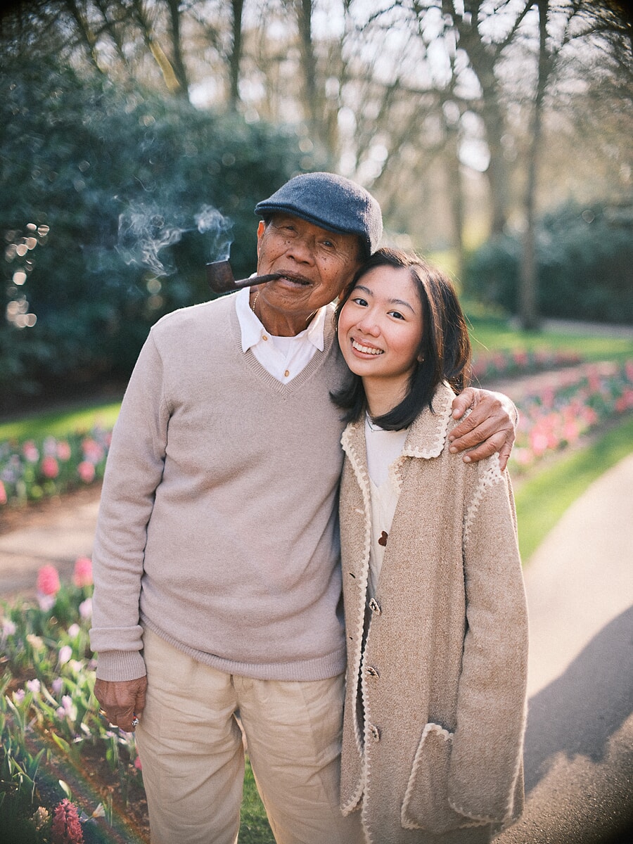 Group Family SP5 Opa met pet rookt een pijp naast zijn lachende kleindochter tussen de voorjaarstulpen, een teder beeld uit een dag vol familiefotografie