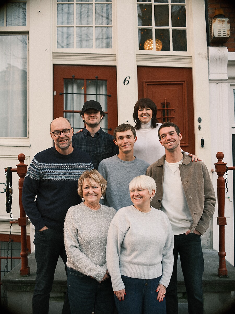 Group Family SP6 Drie generaties op de stoep van een Amsterdams grachtenpand voor een fotosessie ter ere van een huwelijksjubileum, de oma's zittend voor hun kinderen en kleinkinderen