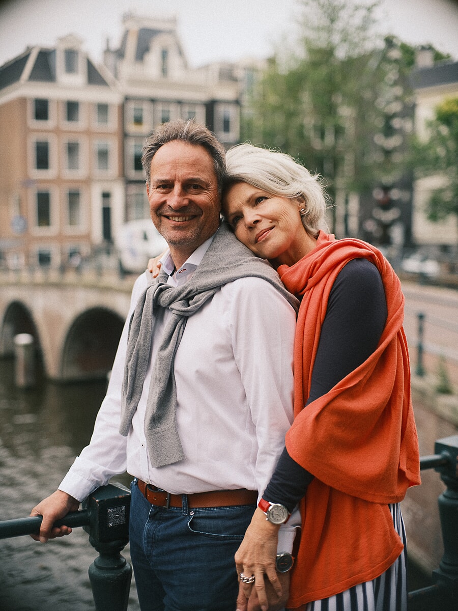 Group Family SP7 Jubileumportretten ter ere van een gouden jubileum: een stel omhelst elkaar bij een Amsterdamse gracht, de vrouw in een oranje omslagdoek met haar hoofd op de schouder van haar partner