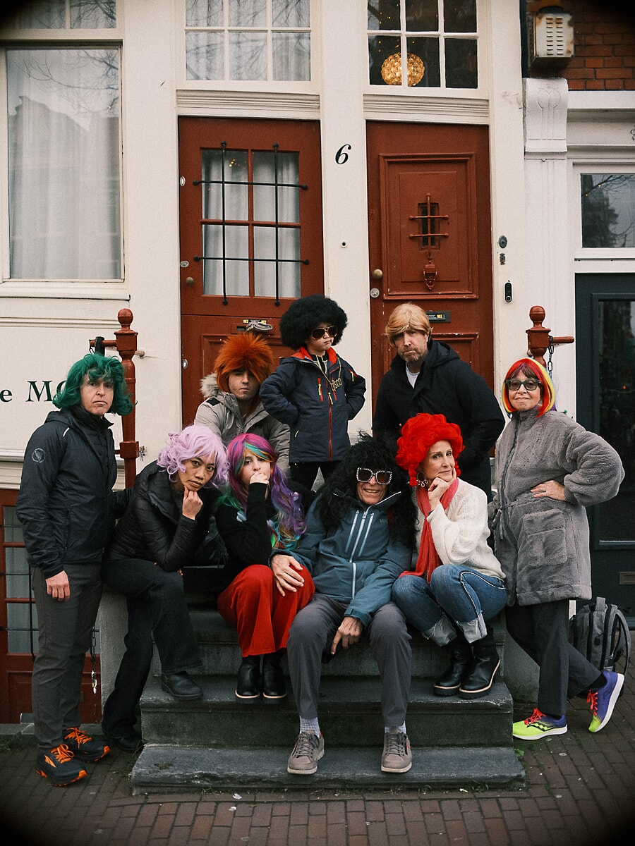 Group Family SP9 Speelse familieportretten van familieleden met felgekleurde pruiken en zonnebrillen op een Amsterdamse stoep