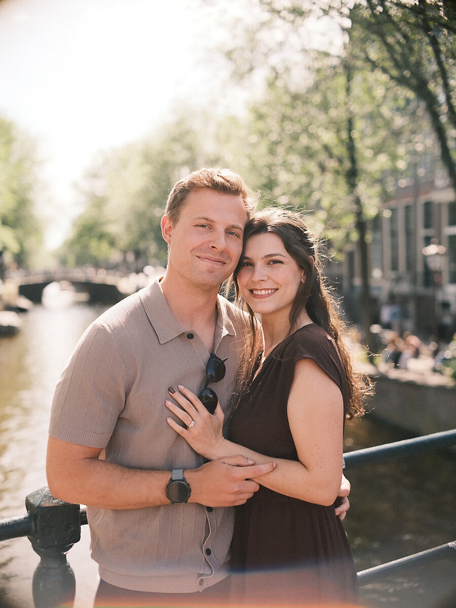 Ontspannen portret van een pas verloofd stel op een Amsterdamse grachtbrug, vlak na het huwelijksaanzoek