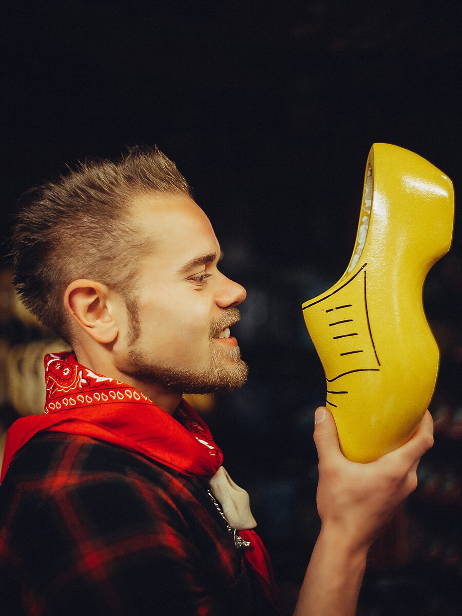 Vakman met een rode bandana houdt een afgewerkte gele klomp omhoog om hem te bekijken in een donkere werkplaats