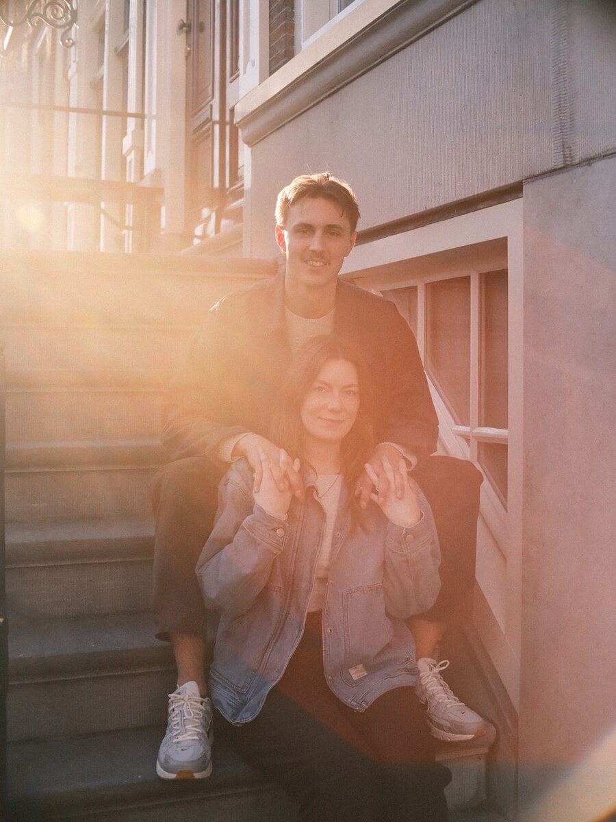 Verloofd stel op stenen treden in het gouden uur tijdens hun verlovingsfotoshoot in Amsterdam