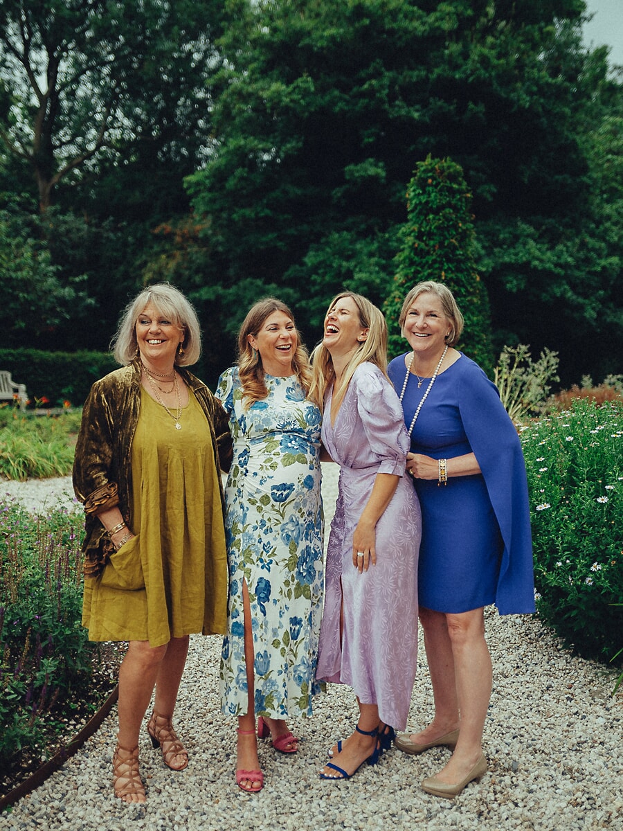 Group Family SP13 Drie generaties vrouwen lachen samen in een groene tuin, oma, moeder en dochters delen een vrolijk moment tijdens hun familieportretten