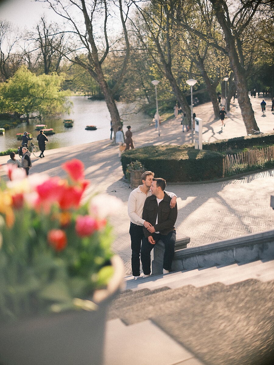 Twee mannen kussen op de trappen van Vondel CS in het Amsterdamse Vondelpark tijdens een loveshoot tussen de tulpen