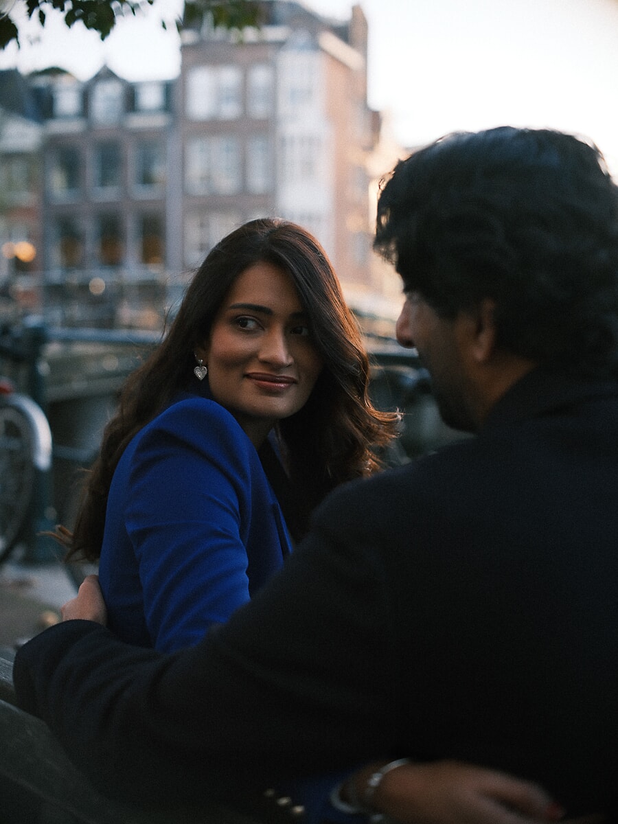 Vrouw kijkt bij schemering over de schouder van haar partner terug langs de gracht