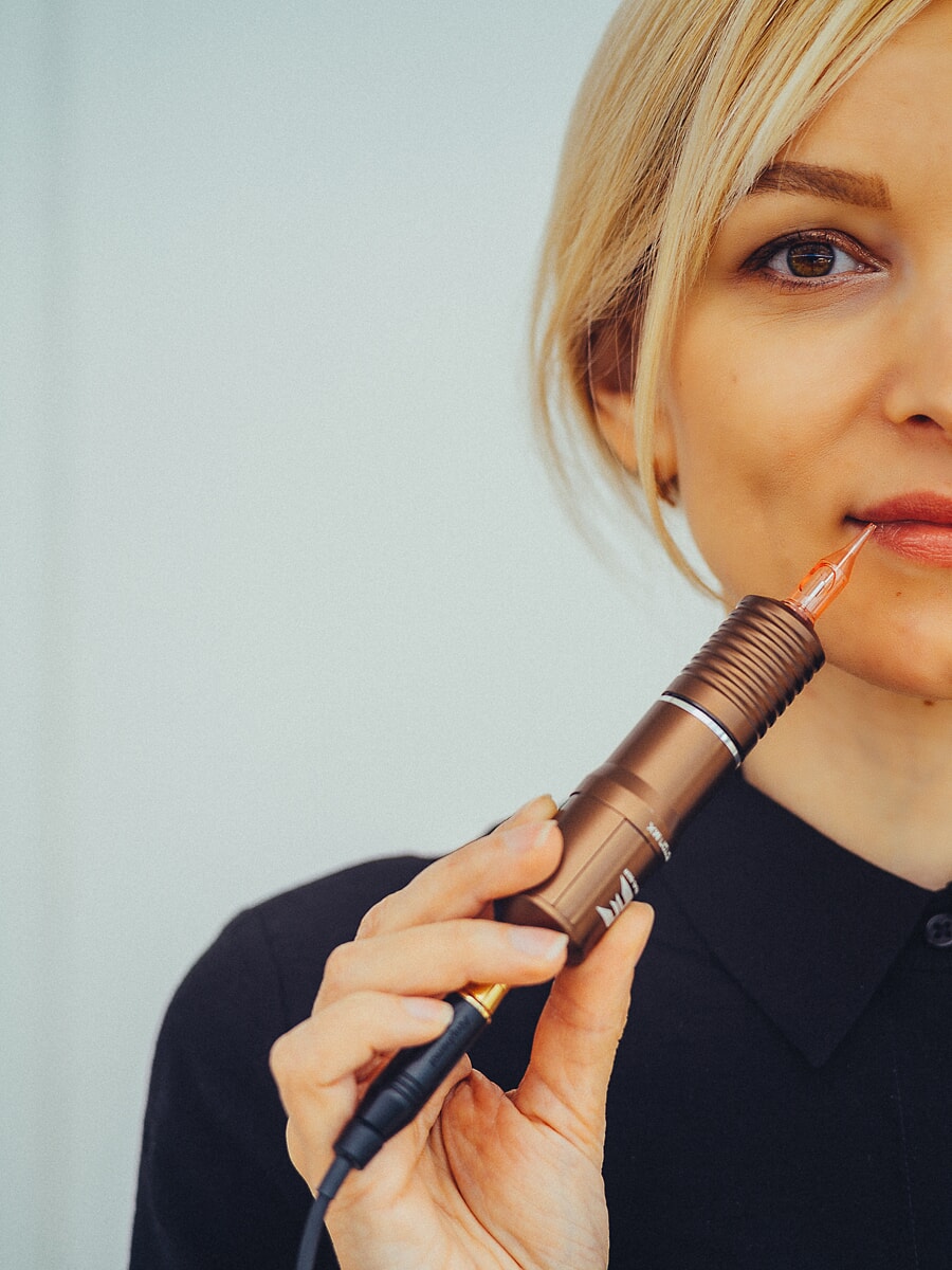 Close-up van een vrouw die een pen voor permanente make-up naast haar lippen houdt