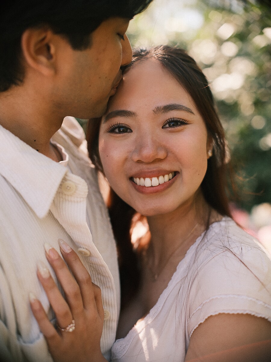 Pas verloofde vrouw straalt bij een voorhoofdkus tijdens de fotoshoot van hun huwelijksaanzoek in Amsterdam