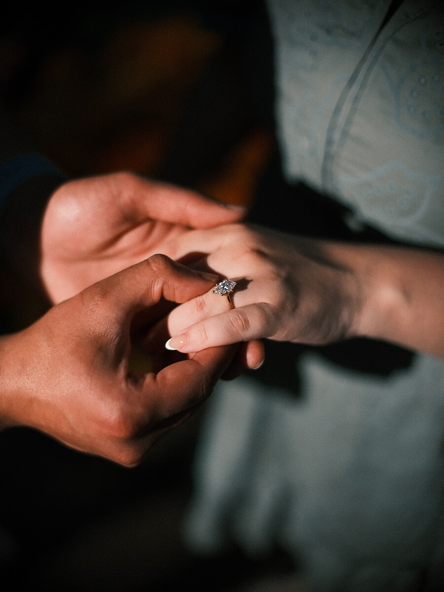 Close-up van de verlovingsring die om haar vinger wordt geschoven in het laatste licht van een verrassingsaanzoek