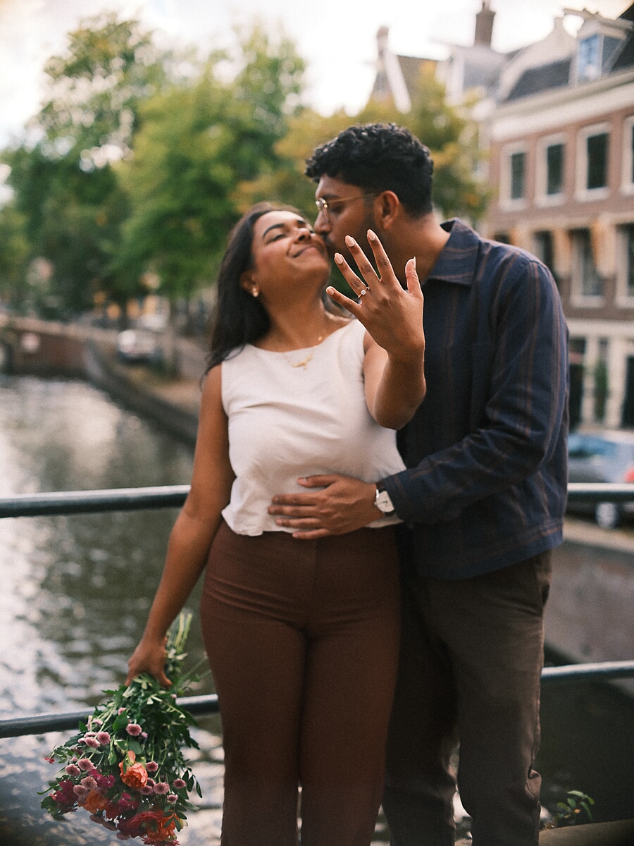 Man kust de slaap van zijn verloofde langs een Amsterdamse gracht terwijl zij haar hand met de verlovingsring opheft
