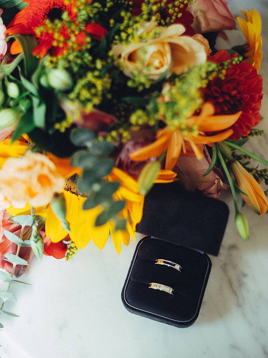 Wedding Ceremony SP15 Gouden trouwringen in een zwart ringdoosje naast een herfstboeket van rozen en zonnebloemen, een gestileerd detail uit de trouwfotografie