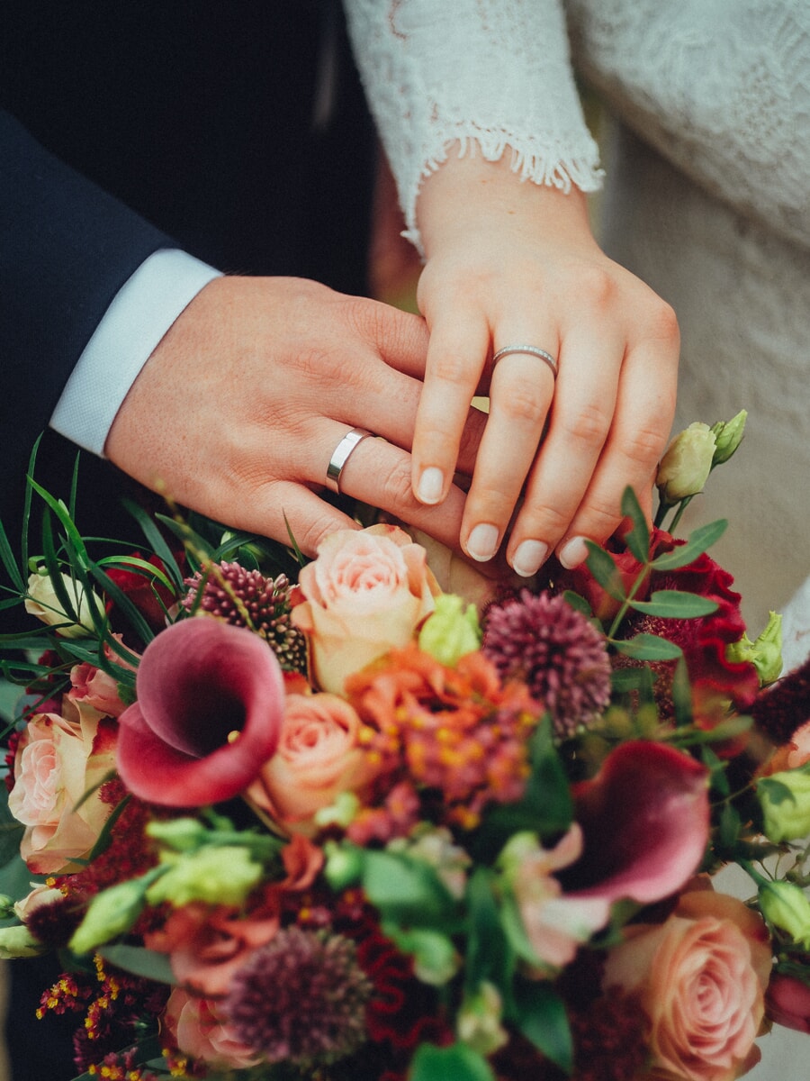 Wedding Ceremony SP26 Pasgetrouwden leggen hun geringde handen op een herfstboeket van rozen en calla's, een intieme huwelijksfoto