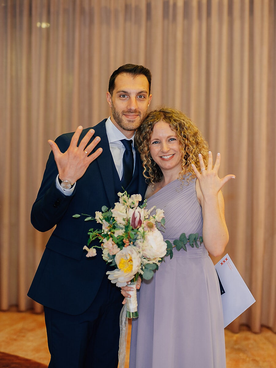 Wedding Ceremony SP33 Net getrouwd stel toont de trouwringen aan de camera, de bruid in lila met haar boeket en trouwakte op het gemeentehuis, een blije huwelijksfoto