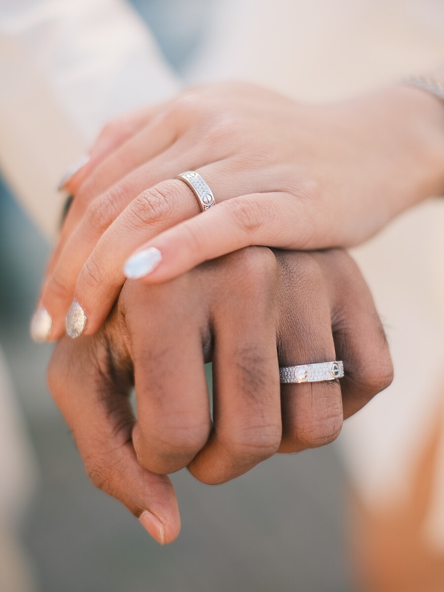 Wedding Ceremony SP5 Detailopname van de in elkaar rustende handen van een pasgetrouwd stel, de met diamant bezette ringen glinsteren in het licht, een fijne huwelijksfoto