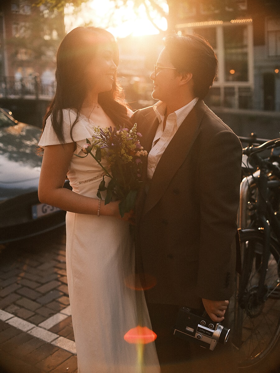 Wedding Bridal SP12 Gouden avondlicht valt op het stel bij de gracht met een veldboeket en oude camera in hun handen, een romantisch beeld