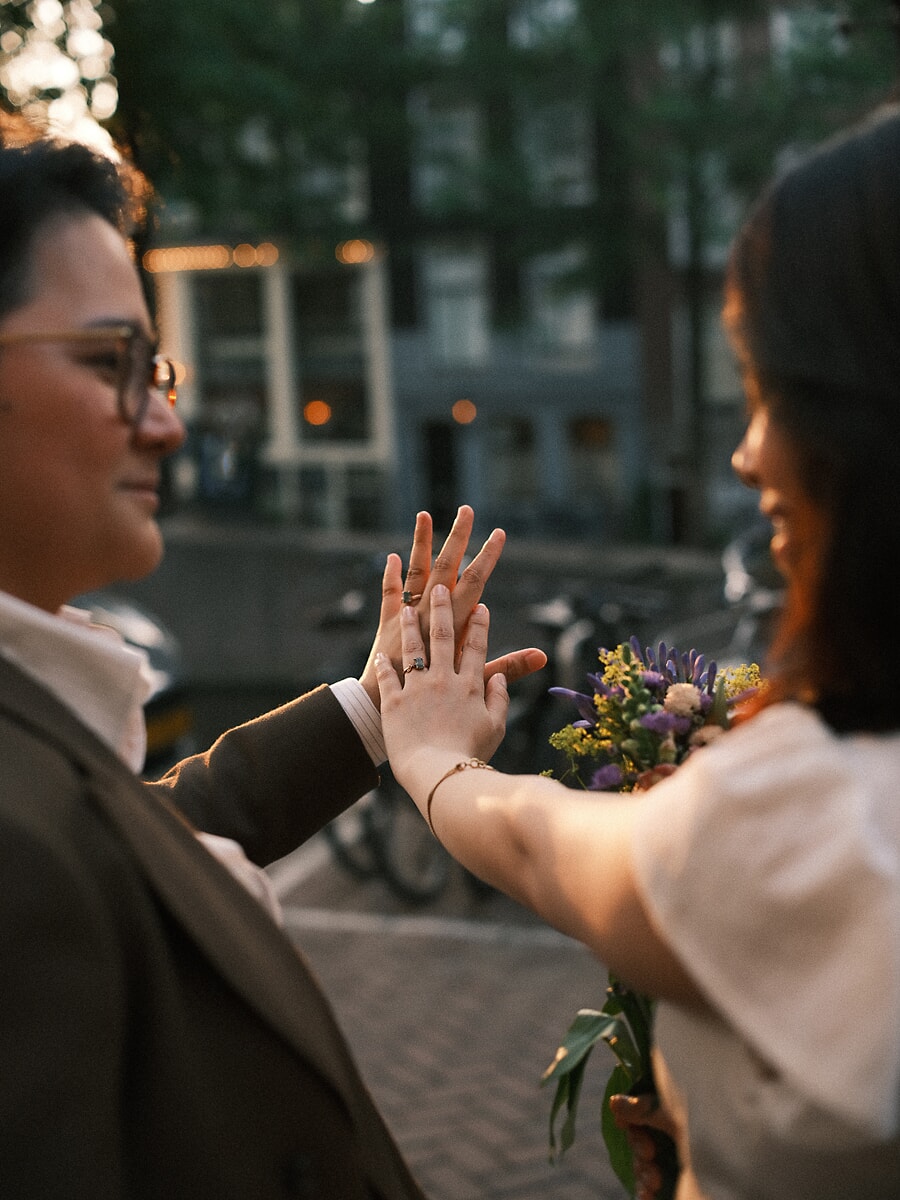 Wedding Bridal SP13 Handpalmen tegen elkaar om hun ringen te tonen op straat, met een veldboeket ertussen, een teder detail uit de bruidsreportage