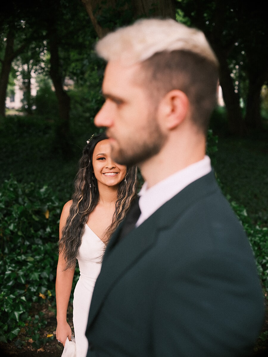 Wedding Bridal SP14 Lachend over de schouder van haar bruidegom tegen een muur van klimop poseert de bruid voor een trouwfotograaf in Amsterdam