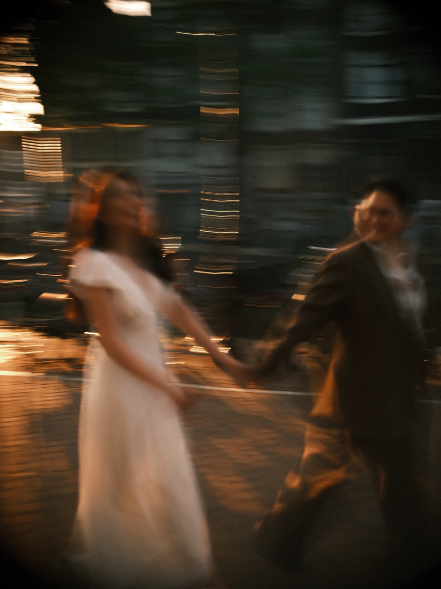 Wedding Bridal SP8 Met bewegingsonscherpte lopen de pasgetrouwden hand in hand door het gouden stadslicht, van een trouwfotograaf in Amsterdam