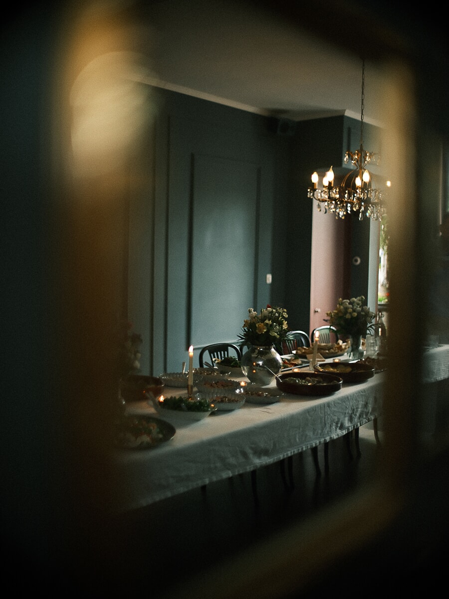 Wedding SP13 Lange gedekte tafel bij kaarslicht met bloemen en zilver weerspiegeld in een antieke spiegel, een ingetogen detail uit de trouwfotografie